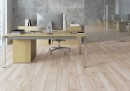 Płytka gresowa, podłogowa imitująca drewno w kolorze beżowym, wykończenie powierzchni matowe, Cerrad Tonella Cream 19,3x120,2 położona na podłodze w biurze gdzie znajduje się krzesło biurko oraz monitor