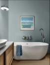 Nowoczesna łazienka w odcieniach błękitu i bieli, ściana za wolnostojącą, owalną wanną jest częściowo wyłożona jasnoniebieskimi płytkami Marazzi Flora Azzurro (30x90 cm, MP7Z), ułożonymi w delikatny wzór jodełki lub chevronu, na ścianie wisi obraz