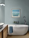 Nowoczesna łazienka z wolnostojącą, owalną wanną, ściana jest pomalowana na szaroniebieski kolor, a jej dolny pas pokrywają trójwymiarowe płytki Marazzi Flora 3D Spike Azzurro 30x90 cm, MP85 w pasującym odcieniu, ułożone we wzór jodełki/chevronu