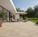 Przestronny taras w ogrodzie, wyłożony beżowymi płytami tarasowymi Marazzi Fabula20 Travertino Cross Beige 100x100 MPMG imitującymi trawertyn, na tarasie znajduje się zestaw wypoczynkowy z sofą, fotelami i stolikiem kawowym, a także duży parasol