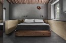 Sypialnia w stylu rustykalnym z nowoczesnym akcentem. Na podłodze widoczne są ciemnoszare płytki ceramiczne imitujące kamień, Marazzi Mystone Pietra Ligure Antracite. Centralnie umieszczone łóżko z ciemną narzutą otoczone jest beżowymi panelami ściennymi
