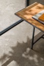 Zbliżenie na fragment nowoczesnego wnętrza z podłogą wyłożoną beżowymi płytkami ceramicznymi Marazzi Mystone Pietra Ligure Beige 120x120 cm MPJJ, które imitują naturalny kamień. W kadrze widoczny jest również narożnik stolika kawowego z rudym blatem