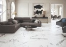 Płytka gresowa, podłogowa imitująca marmur w kolorze białym, wykończenie powierzchni matowe, Durstone Le Blanc Matt 60x120 położona na podłodze w salonie gdzie znajduje się duży szary wypoczynek stolik kawowy oraz przejście do jadalni