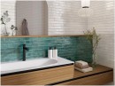Gresowa płytka cegiełka w niebieskim kolorze Oset Ceramiche Menorca Aquamarine 5x50 na ścianie łazienki w połączeniu z drewnianą szafką łazienkową i czarną armaturą