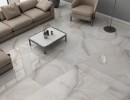 Płytka gresowa, podłogowa imitująca onyks w kolorze szarym, wykończenie powierzchni w połysku, Mykonos Harvey Natural Polished 60x120 położona na podłodze w salonie gdzie znajduje się beżowy wypoczynek oraz stolik do kawy