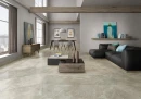 Płytka gresowa, podłogowa imitująca kamień w kremowym kolorze, wykończenie powierzchni w połysku, Pamesa Arezzo Crema Polished 60x60 położona w salonie na podłodze gdzie znajduje się ciemny wypoczynek, stolik kawowy oraz stół jadalny