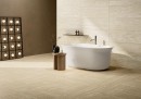 Gresowa ścienna płytka dekoracyjna strukturalna Fioranese Senzatempo Riga Beige Naturale 90,6x90,6 TTR902R na ścianie przestronnej łazienki w połączeniu z białą wanną wolnostojącą, chromowaną armaturą oraz czarnymi elementami dekoracyjnymi