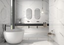 Płytka gresowa, podłogowa imitująca marmur w białym kolorze, wykończenie powierzchni w połysku, Pamesa Cellini Blanco Polished 60x120 położona na podłodze i ścianie w łazience gdzie znajduje się wolnostojąca wanna, stolik na kosmetyki, dwie umywalki