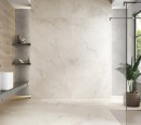 Płytka gresowa, podłogowa imitująca kamień w kolorze beżowym, wykończenie powierzchni satynowe, Pamesa Creta Cream Satin 60x60 położona na ścianie i podłodze w łazience gdzie znajduje się prysznic, półki na kosmetyki oraz kwiat ozdobny