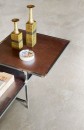 Wnętrze z podłogą wyłożoną jasnymi płytkami Marazzi Mystone Pietra Ligure Bianco R10 60x60 cm MPKD, imitującymi kamień, na stoliku widać dwie mosiężne wazy i ceramiczny akcent, podkreślające nowoczesny, elegancki styl aranżacji