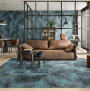 Mieszkanie w stylu industrialnym z jadalnią, salonem z brązową skórzaną sofą wypoczynkową, oddzielonym miejscem na biuro oraz niebieskimi płytkami ścienno-podłogowymi imitującymi metal Caesar Alchemy Navy