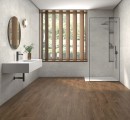 Płytka gresowa, podłogowa imitująca kamień w białym kolorze, wykończenie powierzchni satynowe, Pamesa Sense Blanco Satin 60x60 położona na ścianie w łazience gdzie znajduje się prysznic, wisząca umywalka oraz okrągłe lustro