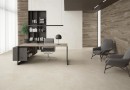 Płytka gresowa, podłogowa imitująca beton w beżowym kolorze, wykończenie powierzchni matowe, Pamesa Argile Ivory Matt 60x120 położona na podłodze w gabinecie gdzie znajduje się stół, krzesła oraz szafka na książki