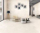 Płytka gresowa, podłogowa imitująca kamień w kolorze beżowym, wykończenie powierzchni matowe, Netto Ceramika Leo Crema Quartz Matt Carving 60x120 położona na podłodze i ścianie w pomieszczeniu gdzie znajduje się krzesło, stolik oraz lampa stojąca