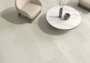 Płytka gresowa, podłogowa imitująca kamień w kolorze beżowym, wykończenie powierzchni matowe, Pamesa Dorset Marfil Matt 120x120 położona na podłodze w pomieszczeniu gdzie znajduje się beżowy fotel oraz stolik kawowy
