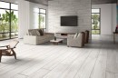 Płytka gresowa, podłogowa imitująca drewno w szarym kolorze, wykończenie powierzchni matowe, Netto Ceramika Boston Grey Matt 20x120 położona na podłodze w salonie gdzie znajduje się wypoczynek, szafka, oraz duże okna na ogród