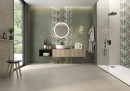 Płytka gresowa, podłogowa imitująca beton w zielonym kolorze, wykończenie powierzchni matowe,Pamesa Eleganza Saggio Matt 60x120 położona na ścianie w łazience gdzie znajduje się prysznic, umywalka, ogrągłe lustro oraz okno z widokiem na ogród