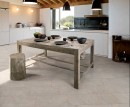 Gresowa podłogowa płytka imitująca kamień Saime Cosmos Calcare Naturale 30x60 7679261 na podłodze kuchni połączonej z jadalnią. Biała zabudowa kuchenna. Stół wykonany z surowego drewna.