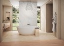 Luksusowa łazienka z wanną wolnostojącą i podłogą z beżowego gresu Marazzi Mystone Tivoli Beige R10, podłoga z antypoślizgowością R10 łączy się z drewnianymi panelami, a duże okna otwierają widok na zieleń