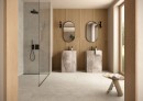 Nowoczesna łazienka z podłogą i ścianą prysznicową wyłożoną szarymi płytkami Marazzi Mystone Tivoli Grigio 120x120 cm MQAP, Ppytki imitujące kamień tworzą neutralne tło dla podwójnej umywalki ze szlachetnego kamienia i drewnianych paneli ściennych