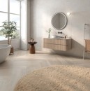 Płytka gresowa, podłogowa imitująca marmur w kolorze kremowym, wykończenie powierzchni matowe, Pamesa Hermes Cream Antic 60x120 położona na ścianie w łazience gdzie znajduje się wanna, drewniana szafka oraz wiszące lustro