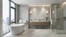 Płytka gresowa, podłogowa imitująca kamień w szarym kolorze, wykończenie powierzchni matowe, Pamesa Manaos Pearl Matt 45x90 położona w łazience na podłodze oraz ścianach  gdzie znajduje się wolnostojąca wanna, prysznic oraz drewniana szafka z umywalką