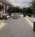 Wizualizacja luksusowego tarasu z basenem wyłożonego szarymi płytkami gresowymi Marazzi Mystone Tivoli20 Grigio 60x60 cm o wyraźnej strukturze kamienia, nowoczesna aranżacja obejmuje eleganckie meble ogrodowe i drzewka oliwne
