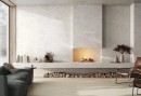 Płytka gresowa, podłogowa imitująca beton w szarym kolorze, wykończenie powierzchni matowe, Pamesa Portlandstone Blanco Matt 60x120 położona na ścianie w salonie gdzie znajduje się kominek, wypoczynek, fotele oraz duże okno