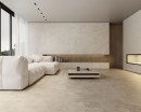Płytka gresowa, podłogowa imitująca beton w beżowym kolorze, wykończenie powierzchni matowe, Pamesa Portlandstone Taupe Matt 60x60 położona na podłodze w salonie gdzie znajduje się jasny wypoczynek, stolik oraz kominek