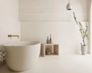 Płytka gresowa, podłogowa imitująca kamień w szarym kolorze, wykończenie powierzchni matowe, antypoślizgowe Pamesa Sospiro Blanco Antislip 60x120 położona na ścianie w łazience gdzie znajduje się wanna, stolik na kosmetyki oraz wisząca lampa