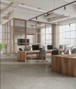 Nowoczesna przestrzeń biurowa o surowym charakterze, w której podłogę wyłożono szarymi płytkami strukturalnymi Marazzi Room Grigio Strutturato 100x100 cm MP6N imitującymi kamień