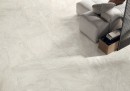 Salon z jasną kanapą i białymi płytkami podłogowymi imitującymi kamień Caesar Quartz Essence Flake