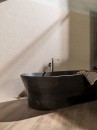 Łazienka z czarną wanną wolnostojącą, drewnianą podłogą oraz płytkami ściennymi Porcelanosa Capri Stone