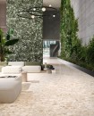 Lobby z płytkami Sant'Agostino Venistone Beige 60x60. Beżowe, matowe lastryko z dużymi jasnymi oczkami ociepla surowy, industrialny beton i zieleń roślin. Włoski design łączący naturę z loftowym stylem.