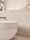 Mozaika dekoracyjna, imitująca kamień w beżowym odcieniu, Lantic Colonial Herringbone Mystic Beige 26x28 100351893 położona na ścianie w łazience z kamienną wanną oraz jasną ścianą