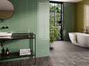 Łazienka w stylu SPA z płytkami El Barco Kendal Laurel 6,5x20. Zielone, szkliwione cegiełki na ścianie tworzą relaksujący klimat, idealnie komponując się z czarną armaturą i widokiem na ogród. Naturalna elegancja i wysoki połysk.