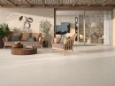 Słoneczny taras wyłożony płytkami Ceracasa Coralina Cream 60x120. Ciepły, beżowy gres o wyglądzie kamienia tworzy idealne tło dla wiklinowych mebli w stylu boho. Matowa powierzchnia harmonijnie łączy wnętrze domu z ogrodem.