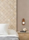 Mozaika dekoracyjna imitująca kamień w beżowym odcieniu, Lantic Colonial Tempo Circle Beige 29,9x29,9 100347807 położona na ścianie w salonie gdzie znajduje się łóżko oraz drewniana szafka