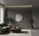 Płytka ścienna imitująca strukturalny gamień w grafitowym odcieniu, wykończenie powierzchni w połysku, Lantic Colonial Allure Titanium 16x16 100380757 położona na ścianie w ciemnym salonie z kanapą, drewnianym stolikiem oraz wiszącym lustrem na ścianie