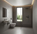 Nowoczesna łazienka wykończona grafitowymi, strukturalnymi płytkami imitującymi kamień, wyposażona w minimalistyczną umywalkę, podwieszaną toaletę oraz prysznic typu walk-in, centralnym punktem pomieszczenia jest wysokie, wąskie okno