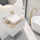 Łazienka z białą wanną wolnostojącą, złotą baterią, białą szafką z drewnianym blatem oraz białą prostokątną nablatową umywalką Oltens  Hadsel 50x40 cm