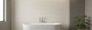 Nowoczesna łazienka z białą wanną wolnostojącą na tle ściany wyłożonej płytkami Marazzi Room Wall 3D Match Bianco 30x90 MP6D, płytki z charakterystyczną, prążkowaną strukturą 3D tworzą subtelną grę świateł i cieni, nadając wnętrzu elegancki charakter