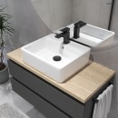 Nowoczesna łazienka z okrągłym lustrem, czarną szafką z drewnianym blatem, czarną baterią oraz białą nablatową umywalką Oltens Hyls