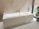 Oltens Langfoss wanna prostokątna 150x70 cm akrylowa biały połysk 10002000 zabudowana płytkami w eleganckiej łazience z rośliną ozdobną oraz dużym oknem