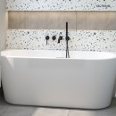 Oltens Delva komfortowa i elegancka wanna wolnostojąca przyścienna 150x70 cm akrylowa owalna biały połysk 12018000 wanna zamontowana przy ścianie w jasnej łazience z płytkami lastryko na ścianie