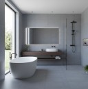 Nowoczesna łazienka, w której ściany i podłogę wyłożono wielkoformatowymi, niebieskoszarymi płytkami Marazzi Slow Cold Piombo 75x75 cm MPE2 o matowej strukturze betonu, wnętrze wyposażono w wolnostojącą białą wannę przy dużym oknie, drewniany blat