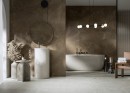 Płytka gresowa, podłogowa imitująca brązowy kamień, wykończenie powierzchni matowe, Cerrad Softstone Brown Rect. 59,7x119,7 położona na ścianie w łazience gdzie znajduje się duża wanna, wolnostojąca umywalka oraz wiszące lampy