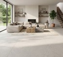 Płytka gresowa, podłogowa imitująca kamień w białym odcieniu, wykończenie powierzchni matowe, Ecoceramic Soft Besana White Matt 100x100 położona na podłodze w dużym salonie gdzie znajduje się jasna sofa, schody na piętro oraz duże okno