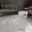 Płytka gresowa, podłogowa imitująca kamień w szarym odcieniu, wykończenie powierzchni rustykalne w macie, Ecoceramic Candy Perla Antic Matt 120x120 położona na podłodze w salonie gdzie znajduje się sofa  oraz fotel