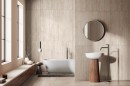 Płytka gresowa, podłogowa imitująca trawertyn w beżowym odcieniu, wykończenie powierzchni matowe, Savoia Travertine Cream Rect. 60x120 położona na podłodze oraz ścianie w łazience gdzie znajduje się wanna, wolnostojąca umywalka oraz wiszące lustro
